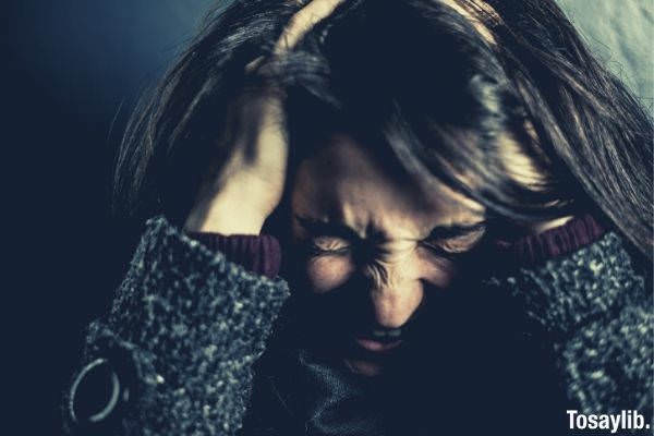 stressed young woman holding her head while in pain