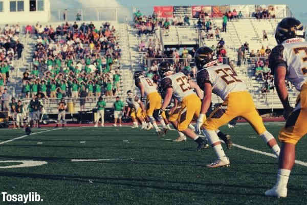 football game photo during daytime players in white and yellow uniform