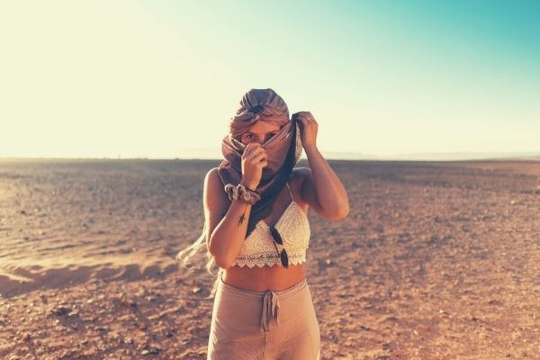 feature-words-to-describe-heat-woman-standing-in-the-middle-of-the-desert-covering-her-face
