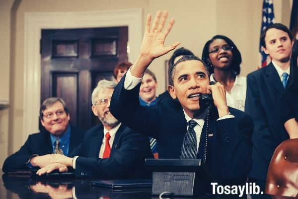 President Barack Obama photo using telephone with other people at the back