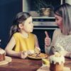 feature-how-to-say-yes-young-girl-in-yelow-mom-in-white-knitted-tops-thumbs-up-to-her-child-eating-cake