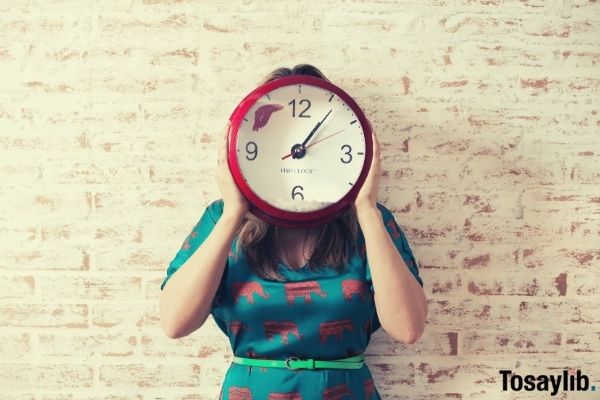 woman in blue dress covering her face with a red wall clock