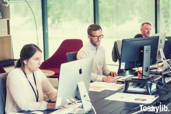 men and woman coworkers sitting in front of their computers working on the table