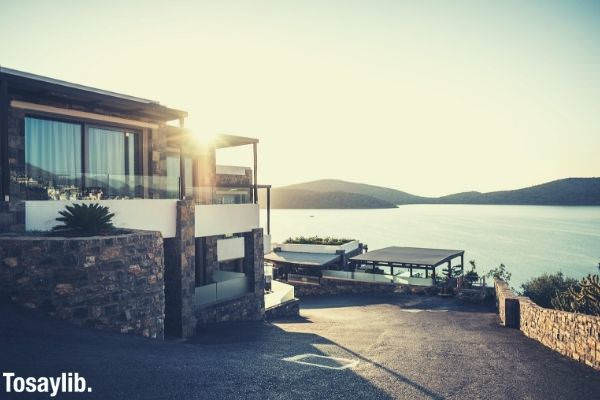 sun rays photo of beautiful brown concrete house near the sea blue skies