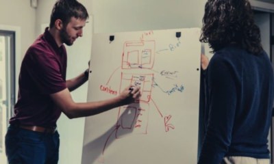 feature-man-writing-on-white-board-talking-with-another-man-in-sweater-ways-to-say-in-conclusion