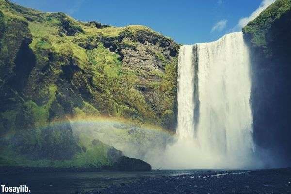 big waterfall green mountain side beautiful rainbow