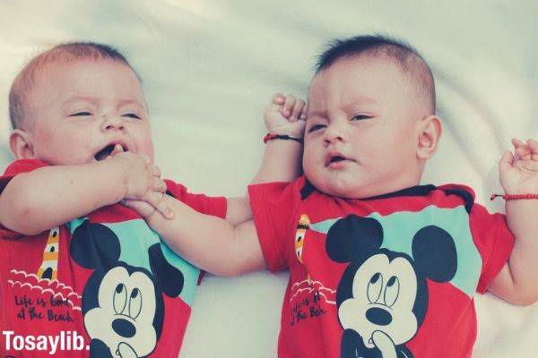 two babies wearing red mickey mouse shirts lying on the bed