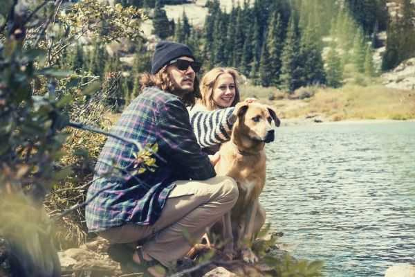 man-and-a-woman-touching-dogs-head-beside-the-lake-looking-on-something-words-to-describe-dogs