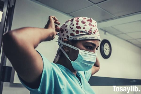woman in teal shirt wearing scrub suit and white surgical mask