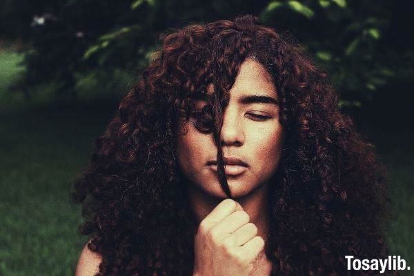 woman with curly hair covering her eyes photo tree grass
