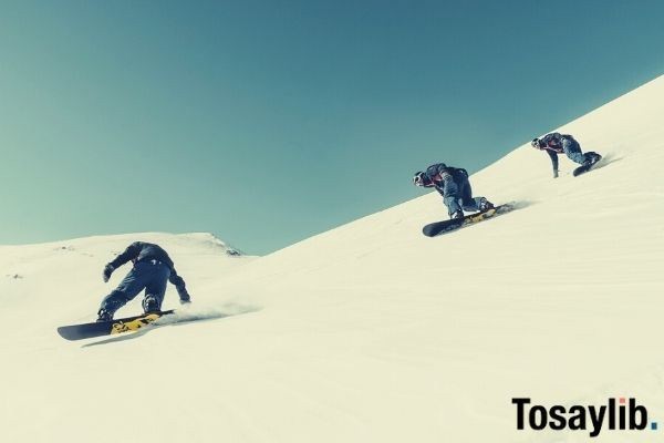 three person riding on snowboard snow sky