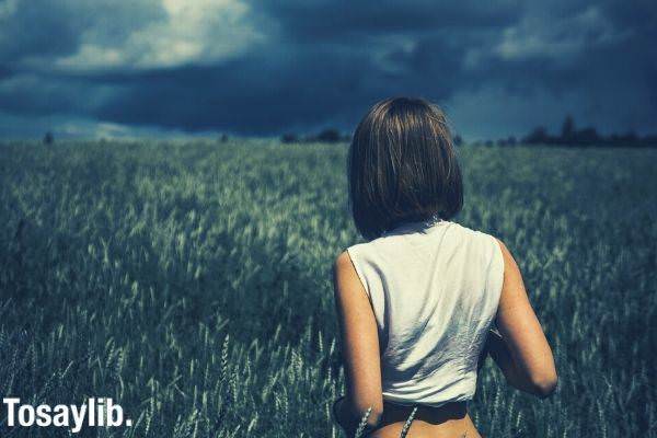 woman in sleeveless top on a grass field cloud