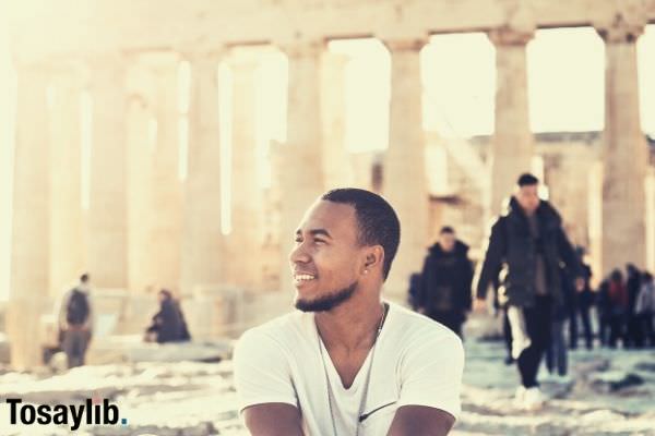 man sitting on white shirt sitting on the rock and monument behind him