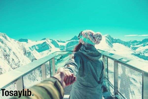 woman holding hands facing backwards near mountains snow