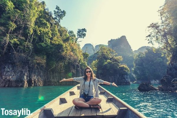 Photo of a woman sitting on the boat spreading her arms smiling