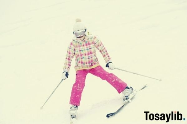 woman in pink skiing snow checkered jacket goggles