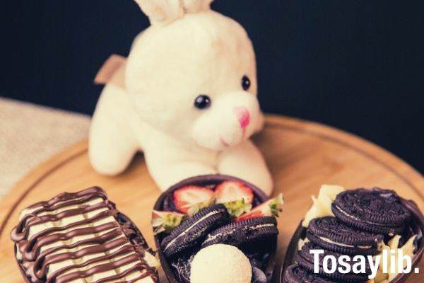 cute plush toy rabbit behind the chocolates on top of round wooden board