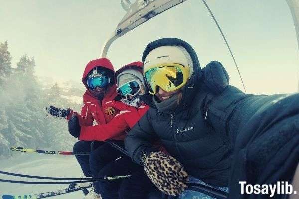 three person wearing ski gear riding on a cable car