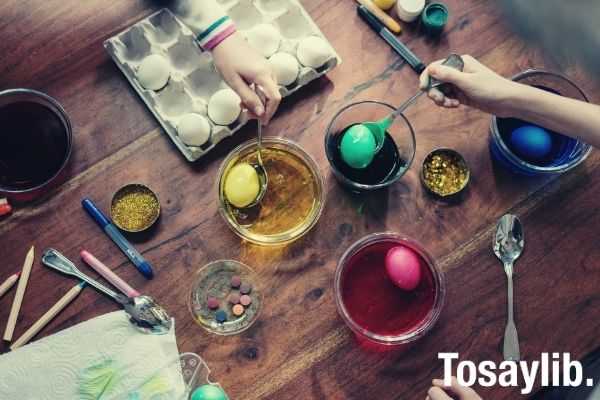 people holding silver spoons with colored eggs on top of table