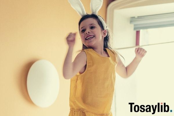 girl in yellow top and white pants with rabbit ears headband jumping on top of bed