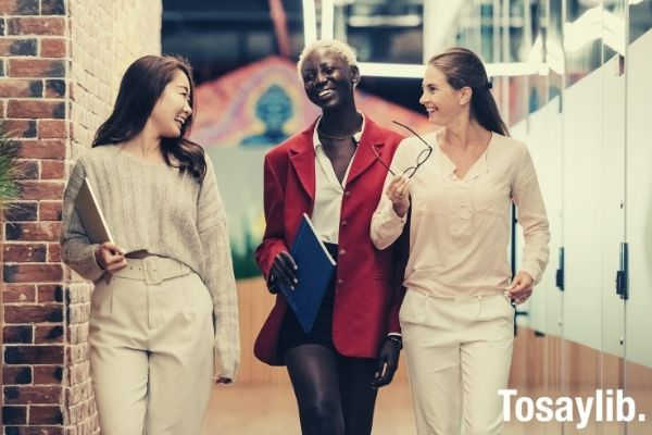 diverse successful businesswomen smiling and walking together in modern workplace