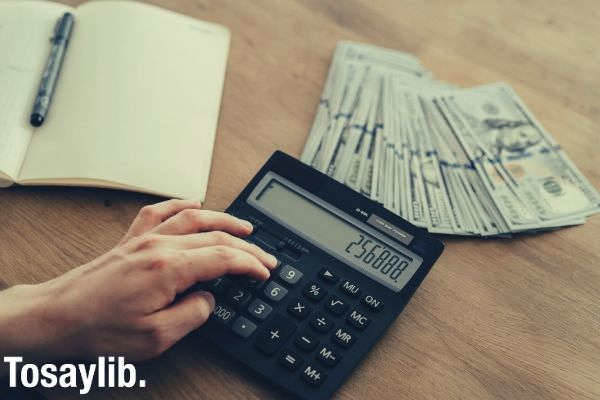 person holding black desk calculator dollar bill notebook