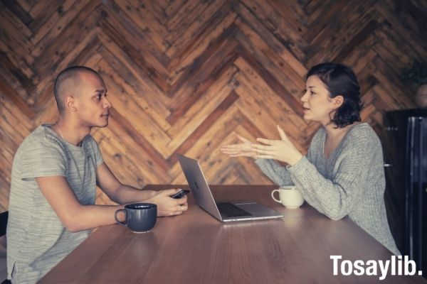 young man looking at the woman in front of him talking about work colleagues