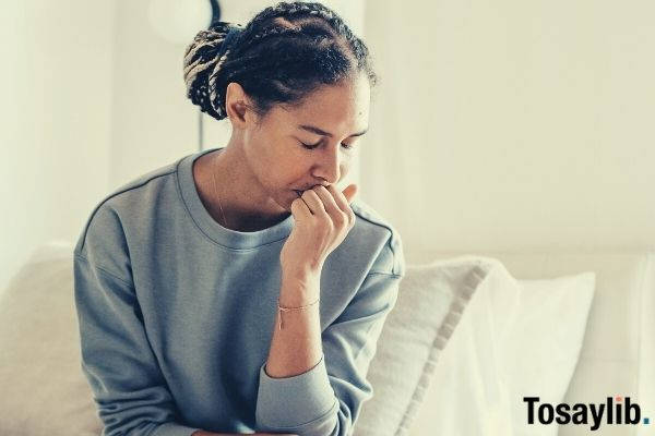 frustrated black woman touching lips and sitting on bed scared crying