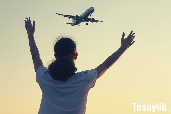 woman in white shirt waving her hand on airplane