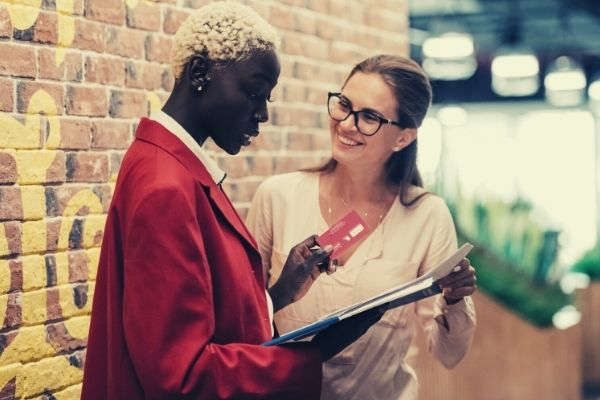 multiethnic-businesswomen-discussing-payment-with-credit-card-brick-wall-words-to-describe-work-ethic