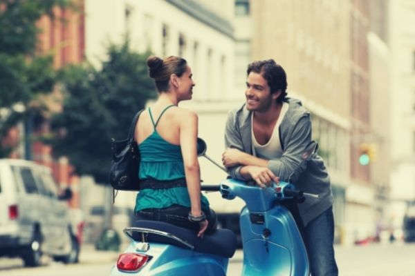 man flirting on a pretty woman sitting on a motorcycle smiling