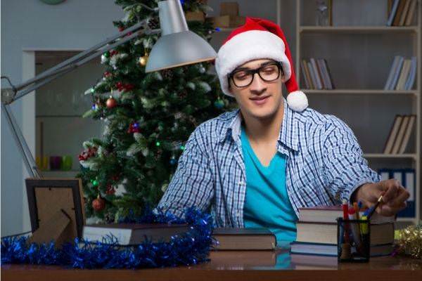 young man doing work at home wearing eyeglasses and christmas hat