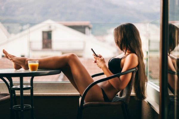 sexy woman using smartphone home balcony