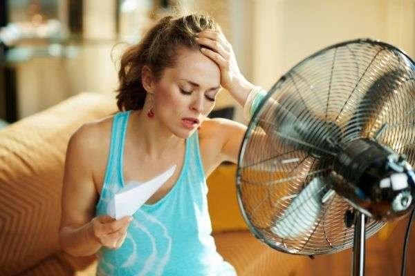 unhappy housewife modern house sunny hot in front of electric fan