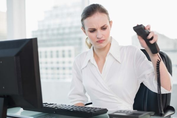 angry businesswoman sitting desk hanging phone