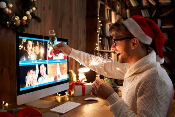 young man wearing christmas hat drinking in front of a monitor