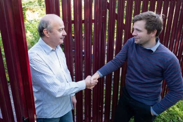 03 two farmers neighbours shaking hands takling beside a wooden fence