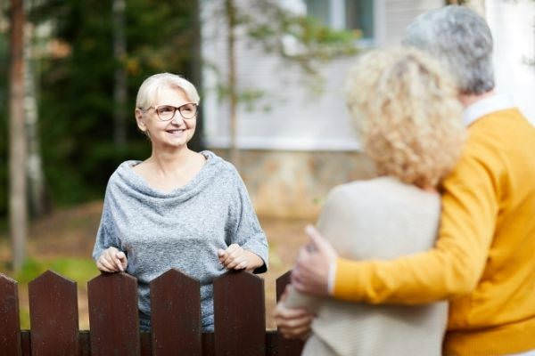 17 blonde mature woman eyeglasses grey pullover leaning on brown wooden fence