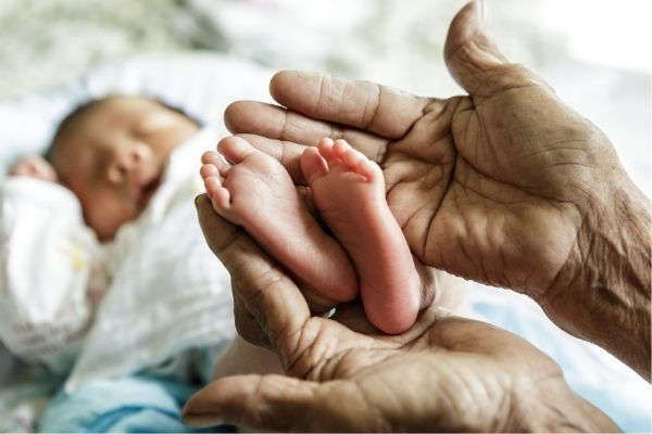 close up photo small baby feet holding by grandparent
