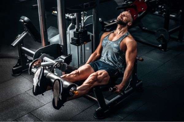 muscular man using weights machine legs