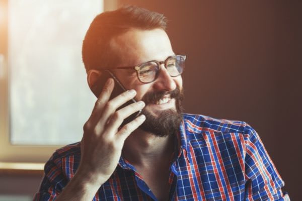 bearded man wearing blue and red stripes using phone smiling
