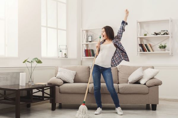 happy woman cleaning home singing mop