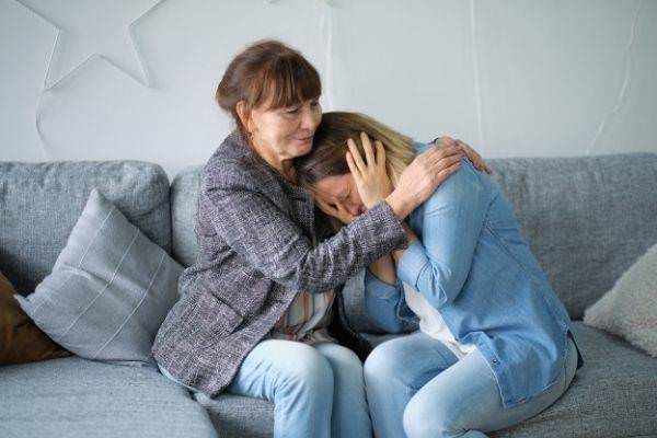 elderly mother hug crying adult daughter
