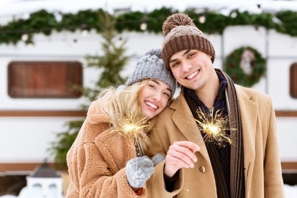 smiling romantic couple knitted hats posing holding sparklers