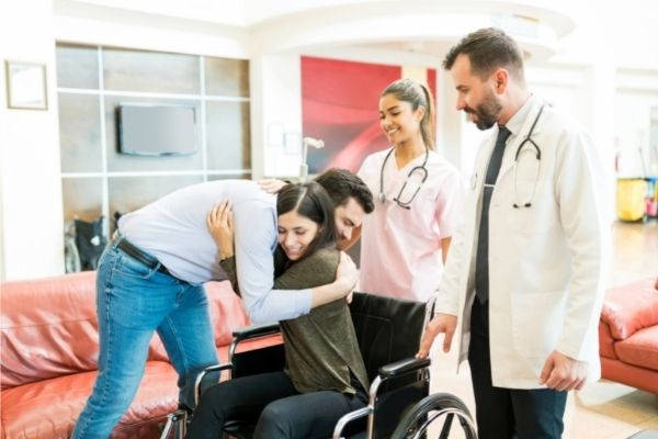 doctors looking man embracing woman on wheelchair