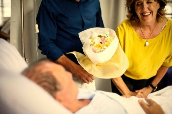 03 sick elderly man staying hospital visitors brought flowers