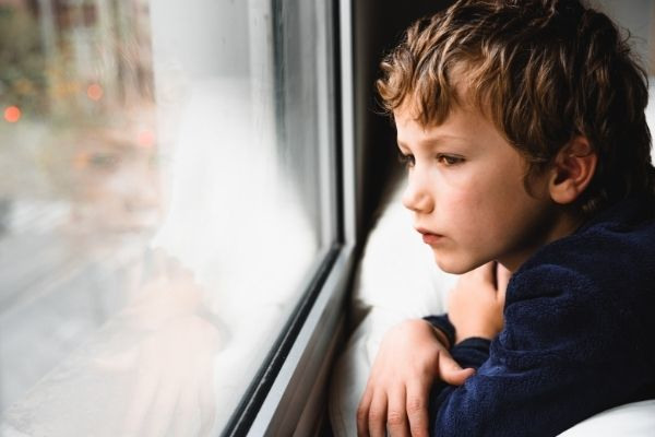 boy stays home bored by school looking outside the window