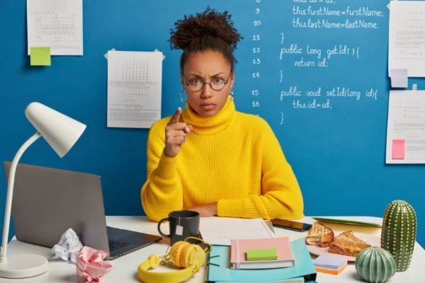 annoyed afro american woman worker points wearing yellow sweater
