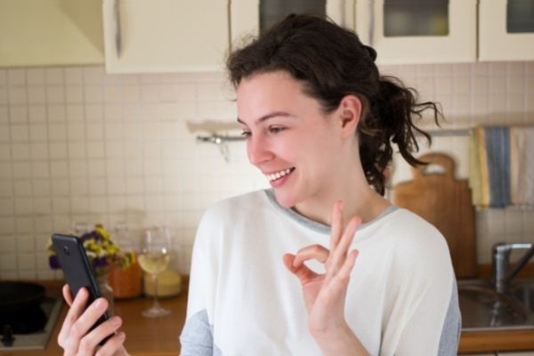 cheerful millennial caucasian curly woman using looking at her phone