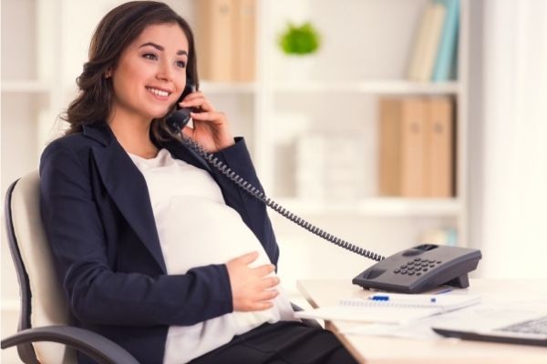 happy pregnant woman talking on phone touching her stomach